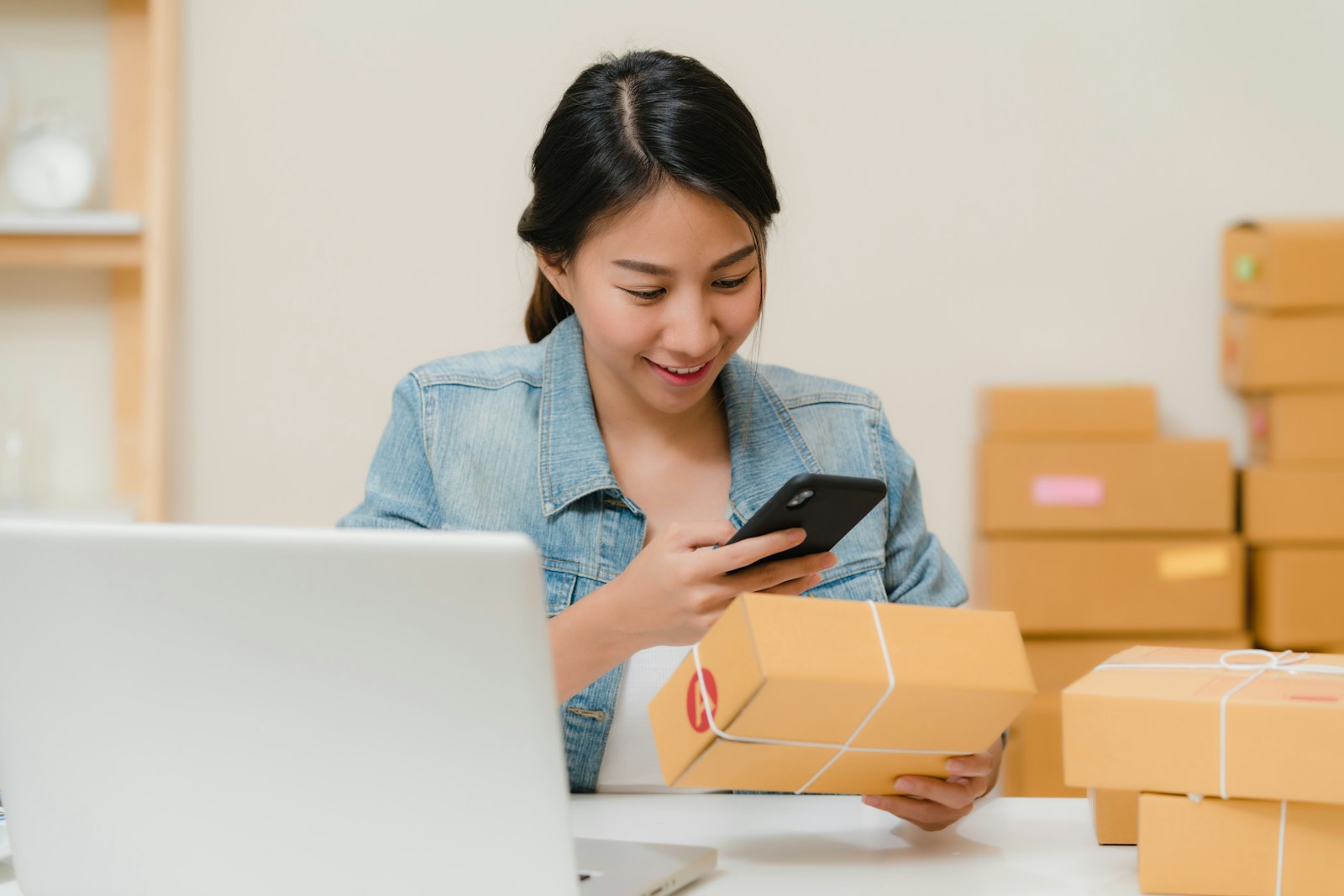 Entrepreneur holding a package while looking at her phone